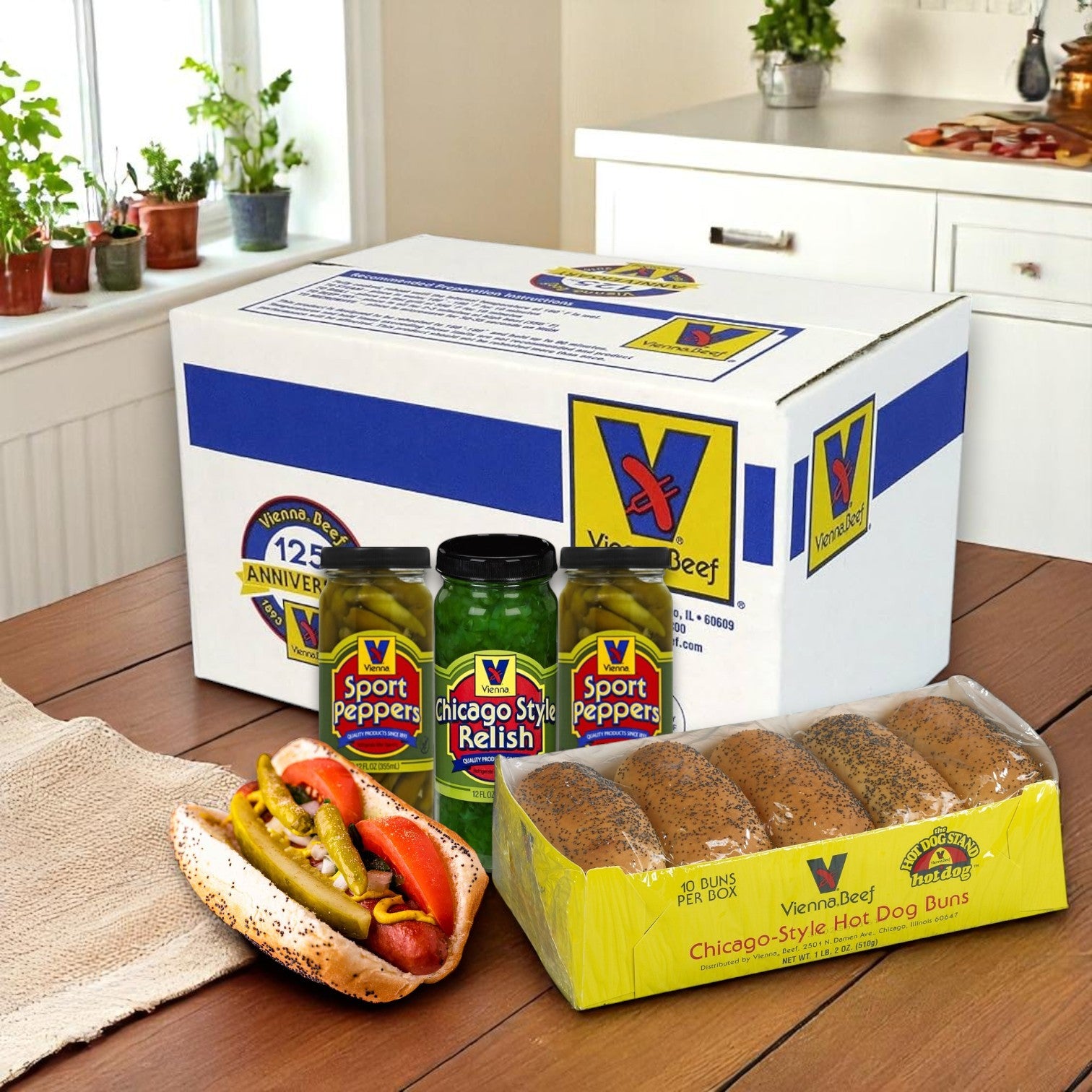 Vienna Beef Chicago-Style Hot Dog Combo – 60 Pack sits on a kitchen table, featuring jars of sport peppers, Chicago-style relish, poppy seed hot dog buns, and a classic hot dog—perfect for your next BBQ party!.