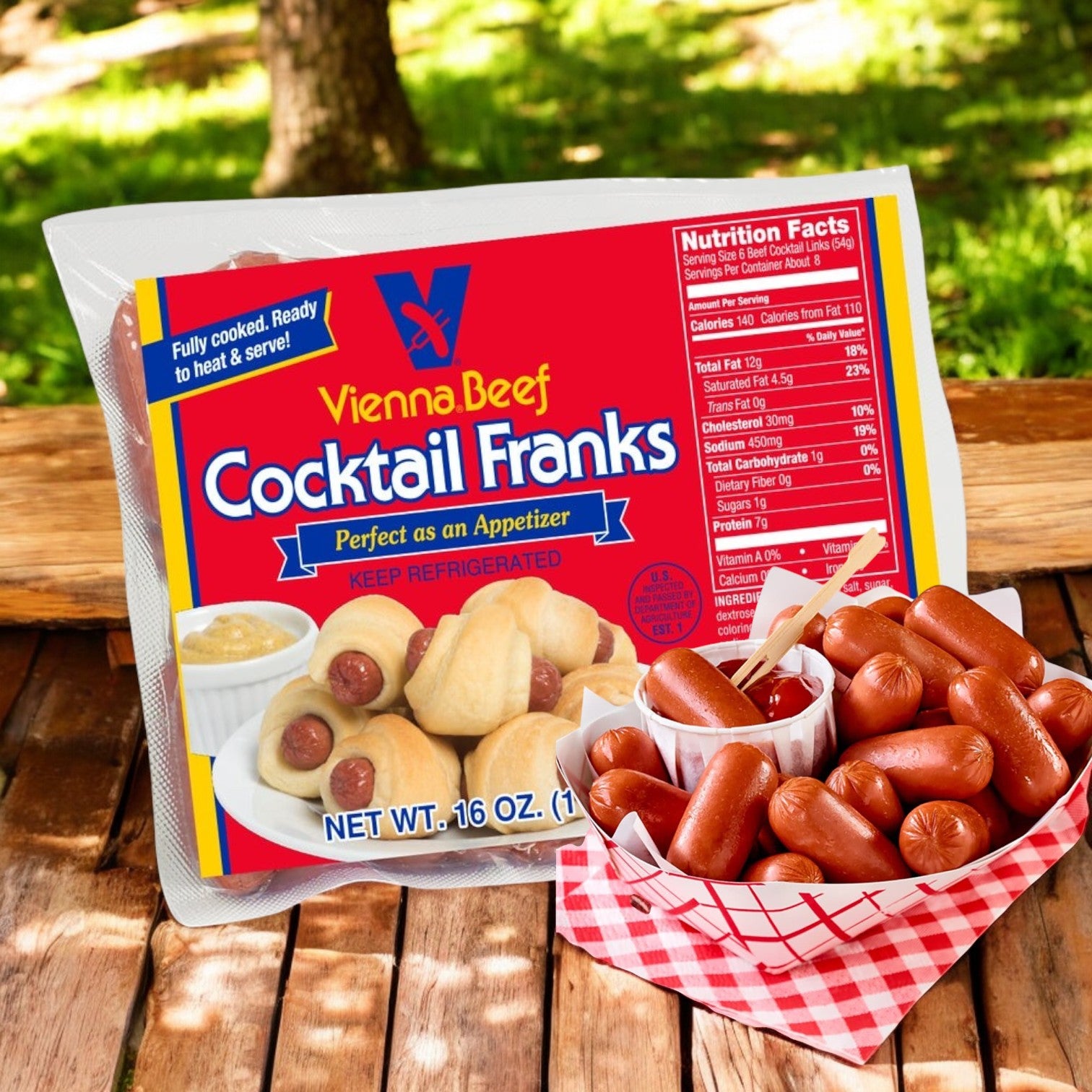 A package of Vienna Beef Cocktail Franks- 3 Count by Vienna Beef is placed next to a basket overflowing with cooked mini hot dogs, expertly complemented with mustard and a small leaf accentuating the background.