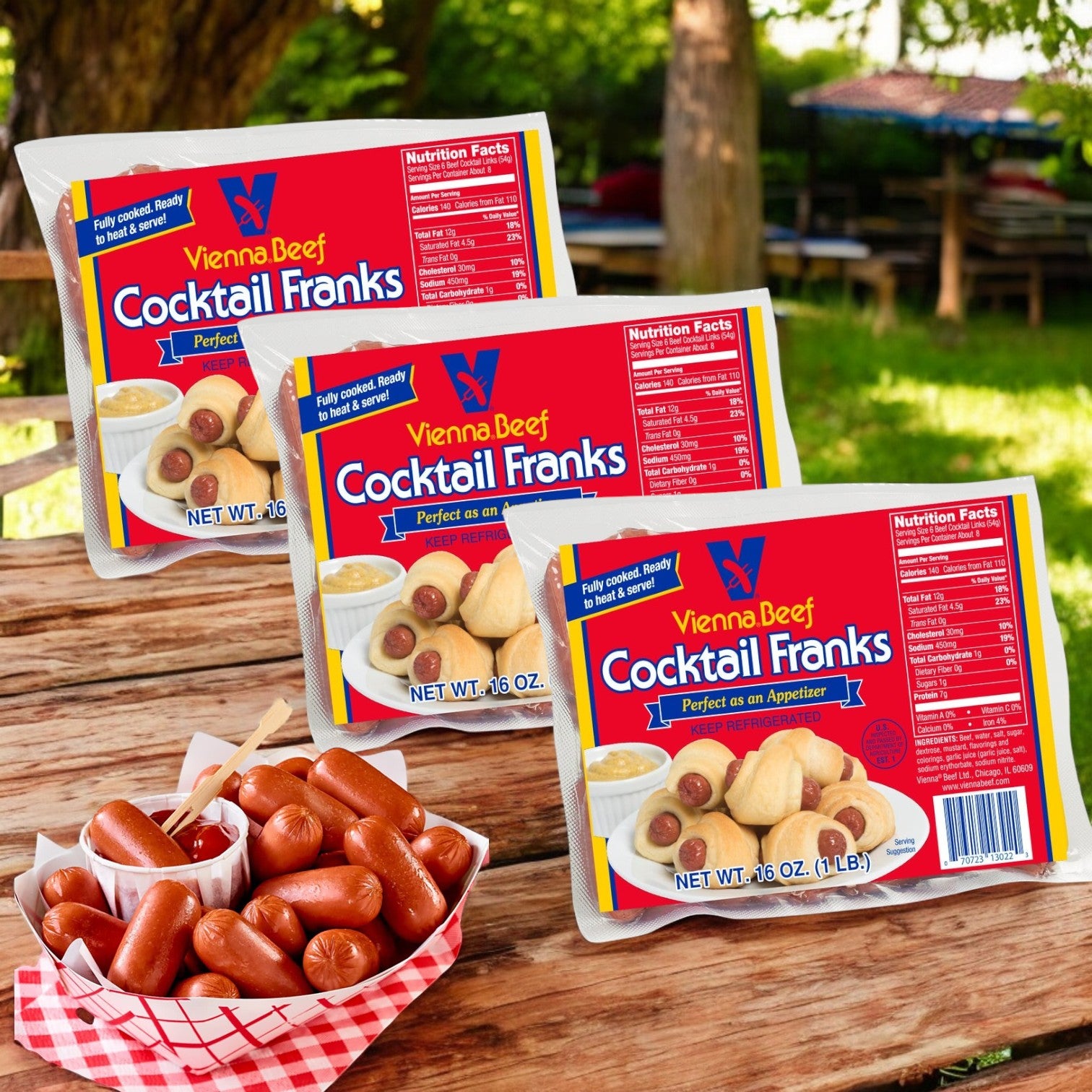 Outdoor wooden tables are adorned with packs of Vienna Beef Cocktail Franks- 3 Count, complemented by a basket of sizzling mini hot dogs prominently displayed in the foreground.