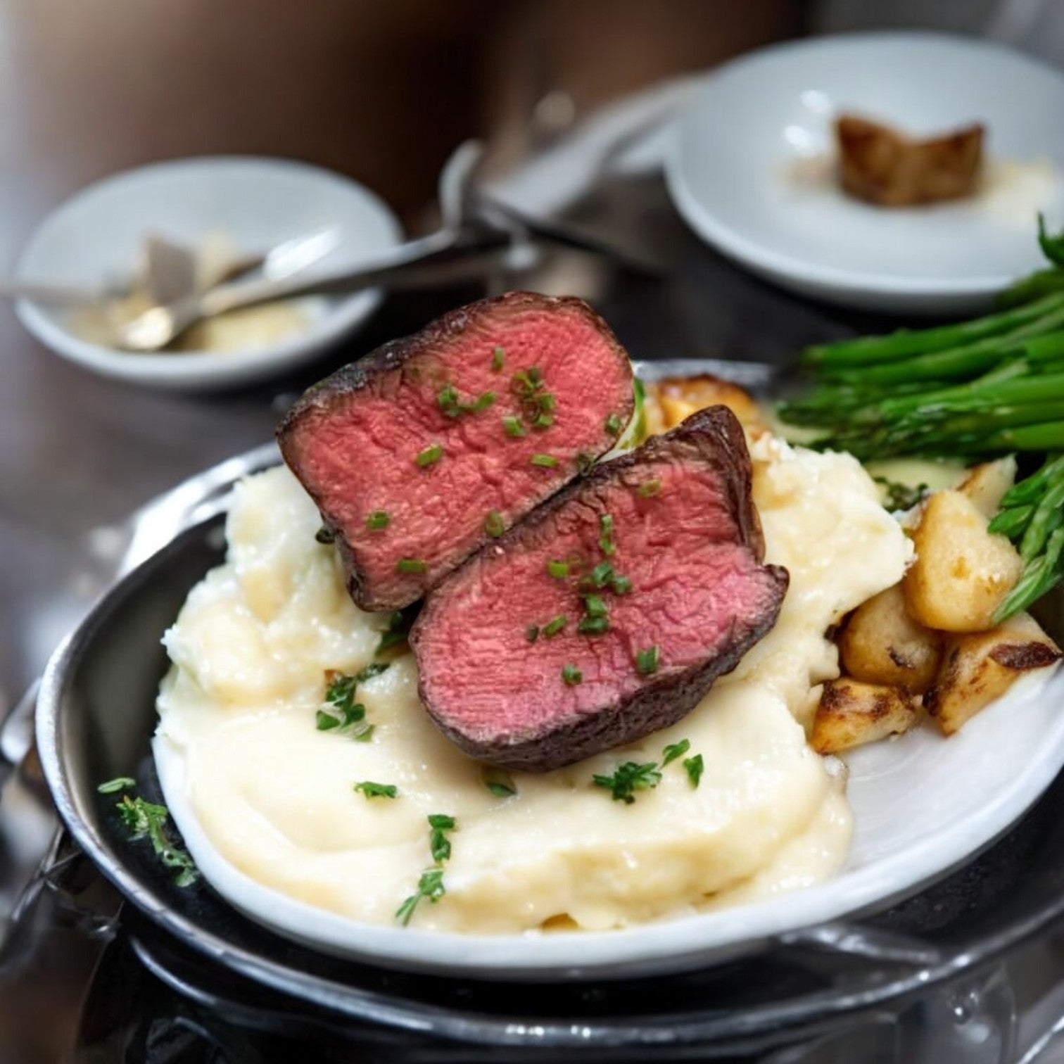 A 6oz filet from Mino Prime Steaks is served sliced over mashed potatoes, with roasted potatoes and asparagus.