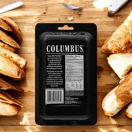 A package of Columbus Herb Roasted Turkey Breast sits elegantly on a wooden board, surrounded by slices of baguette, offering a wholesome choice for those who appreciate premium deli meat.