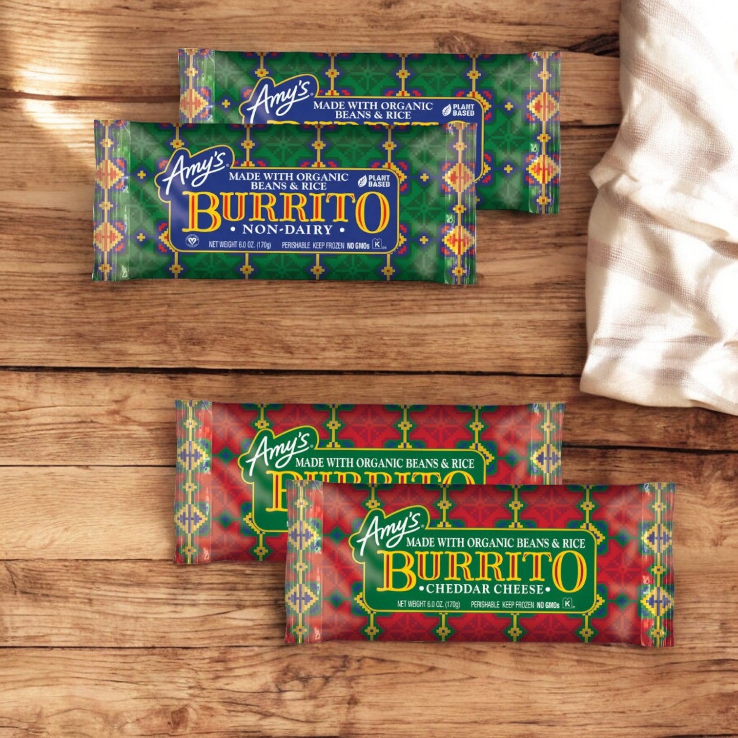 Packets of Amy's Burritos, including 2 Amy's Vegan Bean & Rice and 2 Amy's Bean & Cheese - totaling 4 burritos, displayed on a wooden surface next to a white cloth.