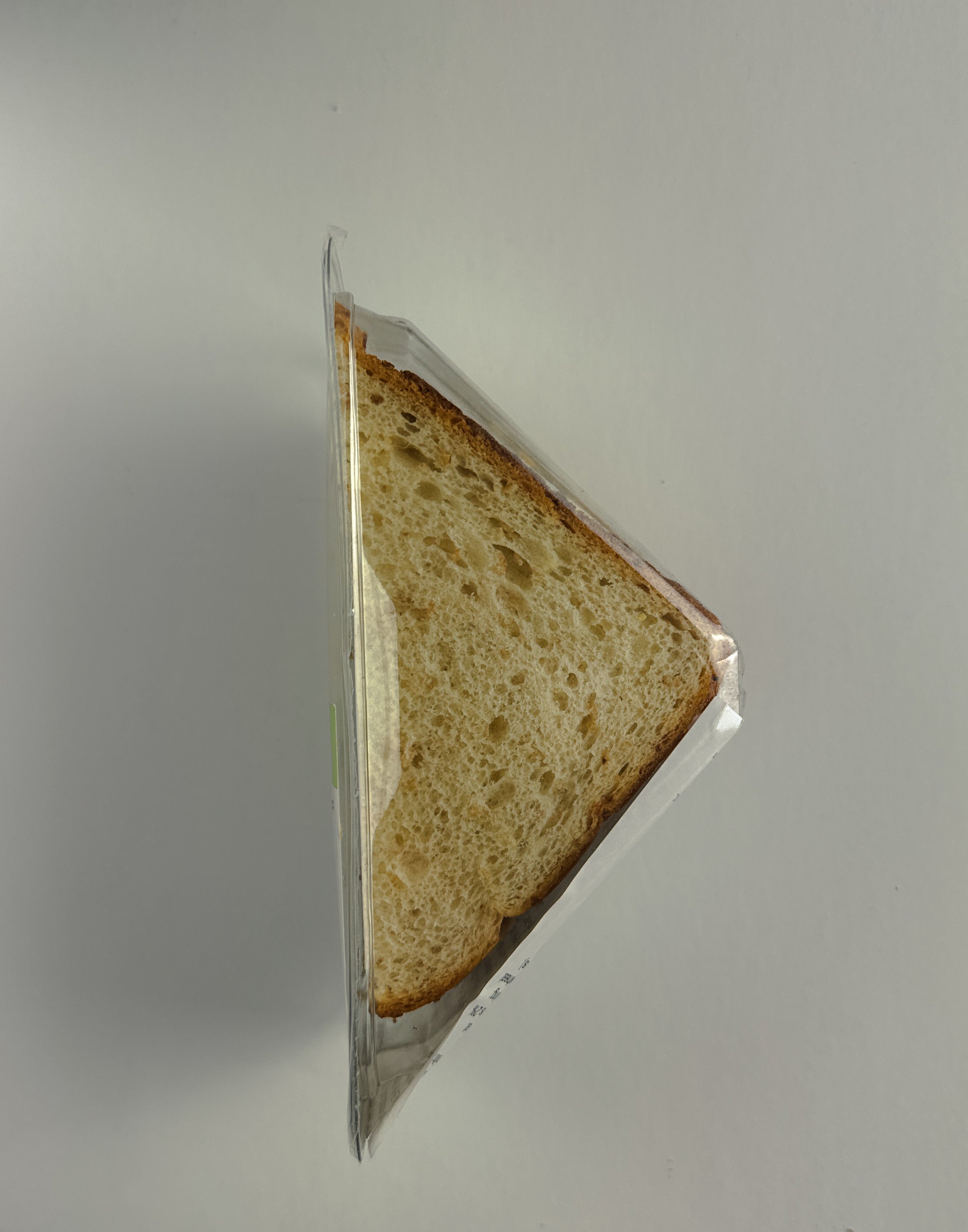 A triangular **Tuna Salad Sandwich** with a delectable filling of Tuna Salad, enriched with Canola Mayonnaise, placed in a clear plastic container by **Taylor Farms**.