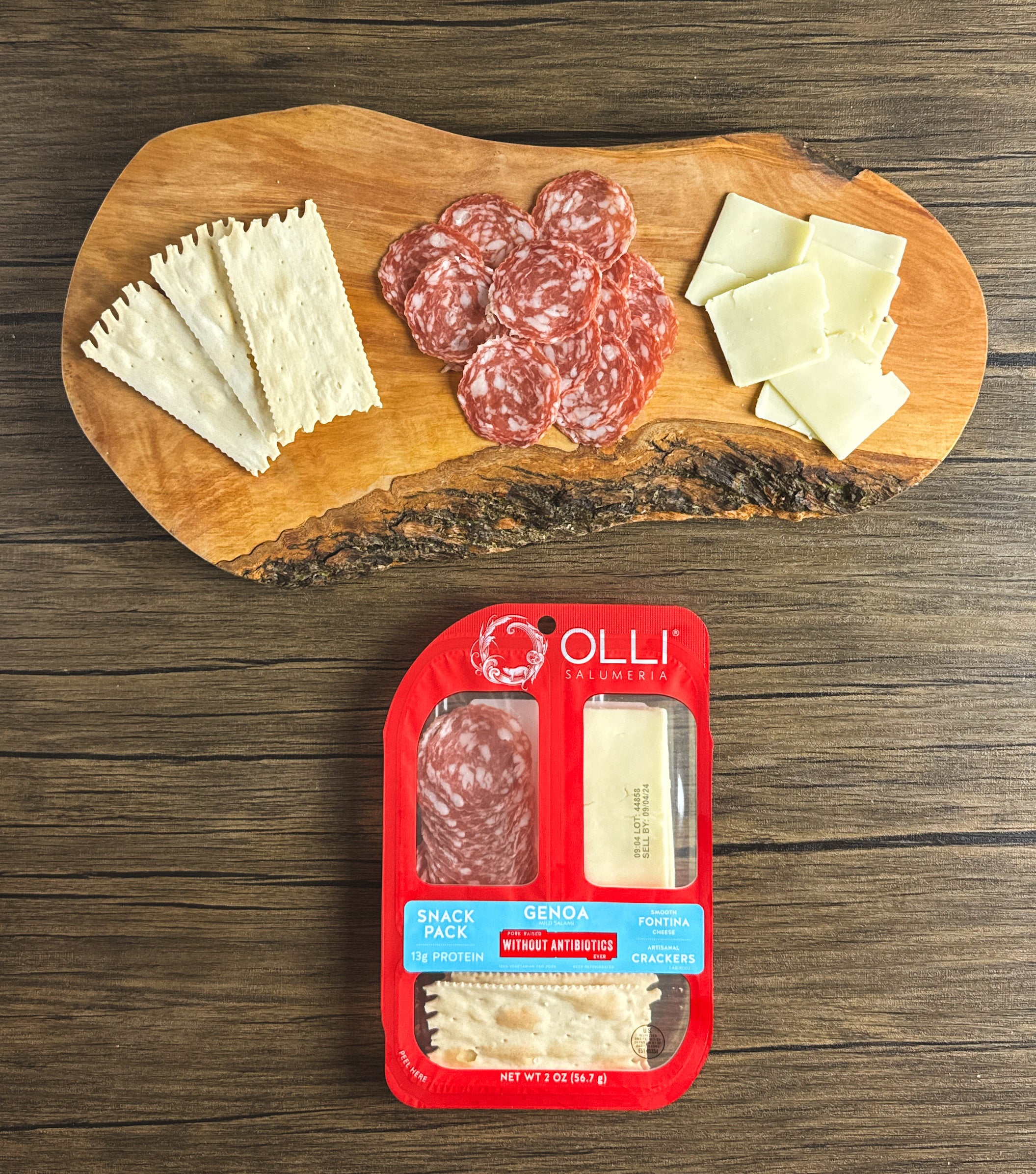 A wooden board with crackers, slices of Genoa salami, and cheese next to an Olli Salumeria Snack Pack Genoa (2 oz, 1 Count) from Olli, featuring artisanal Italian flavors of Genoa salami, Fontina cheese, and crackers.