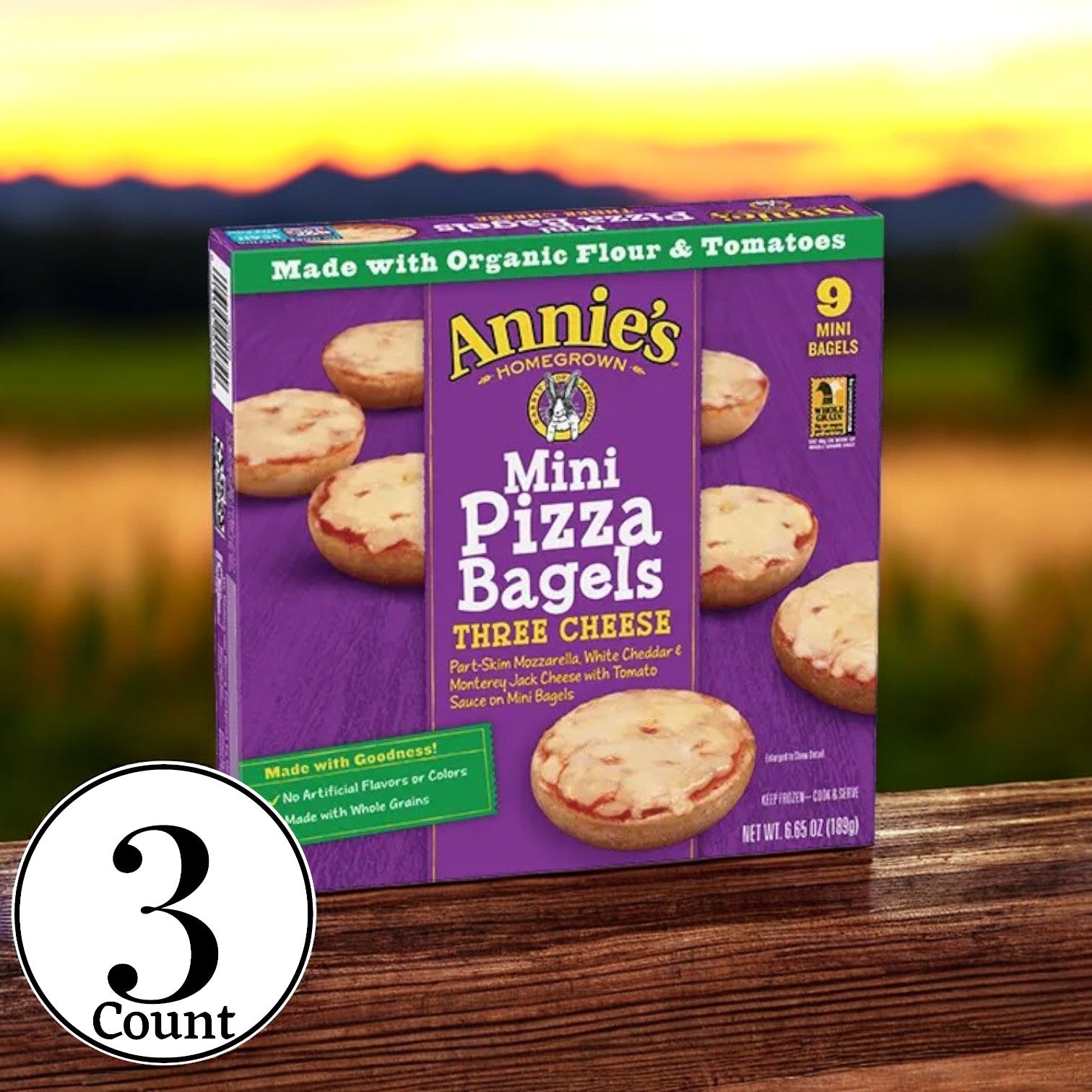 A trio of Annie's Three Cheese Mini Pizza Bagels boxes, presented in an outdoor setting. The packaging prominently highlights its organic ingredients, such as flour and tomatoes, and assures no artificial flavors. Each box contains a total of 9 mini pizza bagels, with the "3 Count" label clearly visible on the front.