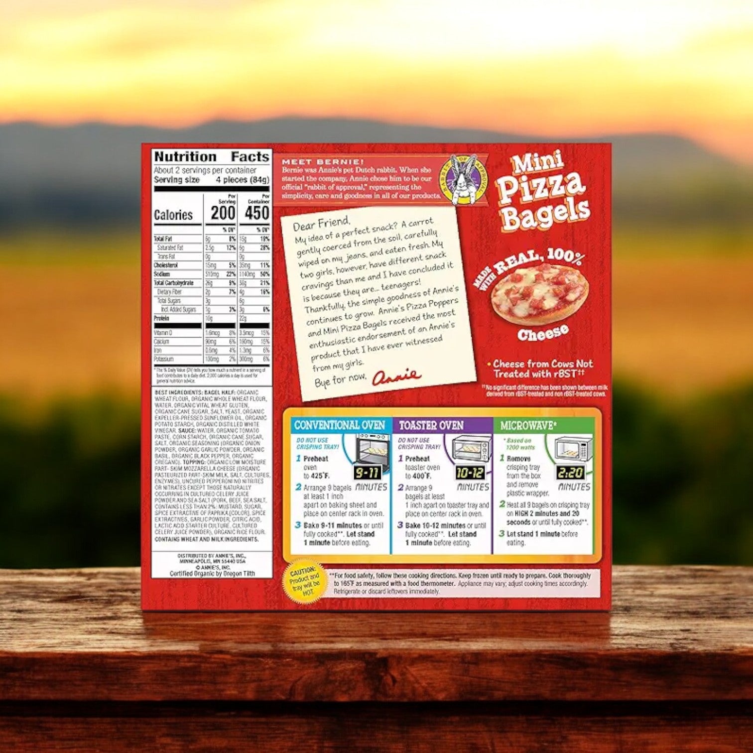 A box of Annie's Uncured Pepperoni Mini Pizza Bagels, sized at 6.65 oz., features nutritional information, cooking instructions, and a brand message from Annie's against a blurred background.