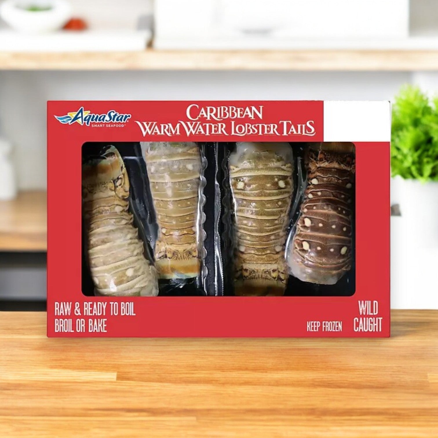 A package of Aqua Star Wild Caught Caribbean Warm Water Lobster Tails on a kitchen counter. The box displays twelve lobster tails in total, as it contains three packs of four frozen tails each, ready to be boiled, broiled, or baked. Experience the premium taste of sustainably harvested seafood with these delicacies. Plus, enjoy the convenience of free shipping!