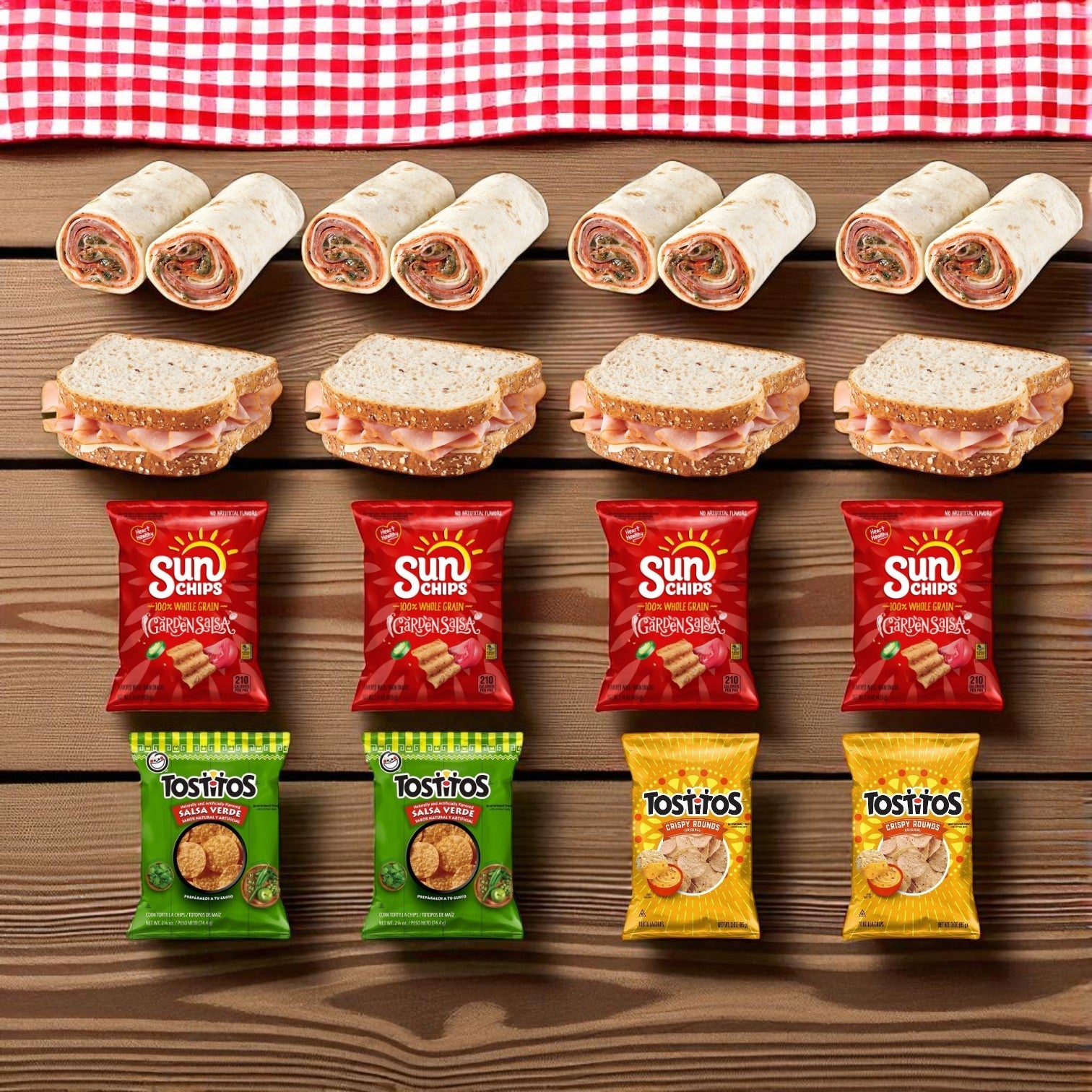 The E.A. Sween Snack & Deli Variety Pack features rows of chips and sandwiches with individually wrapped snacks like Sun Chips or Tostitos, all arranged neatly on a wooden surface with a red and white checkered cloth.