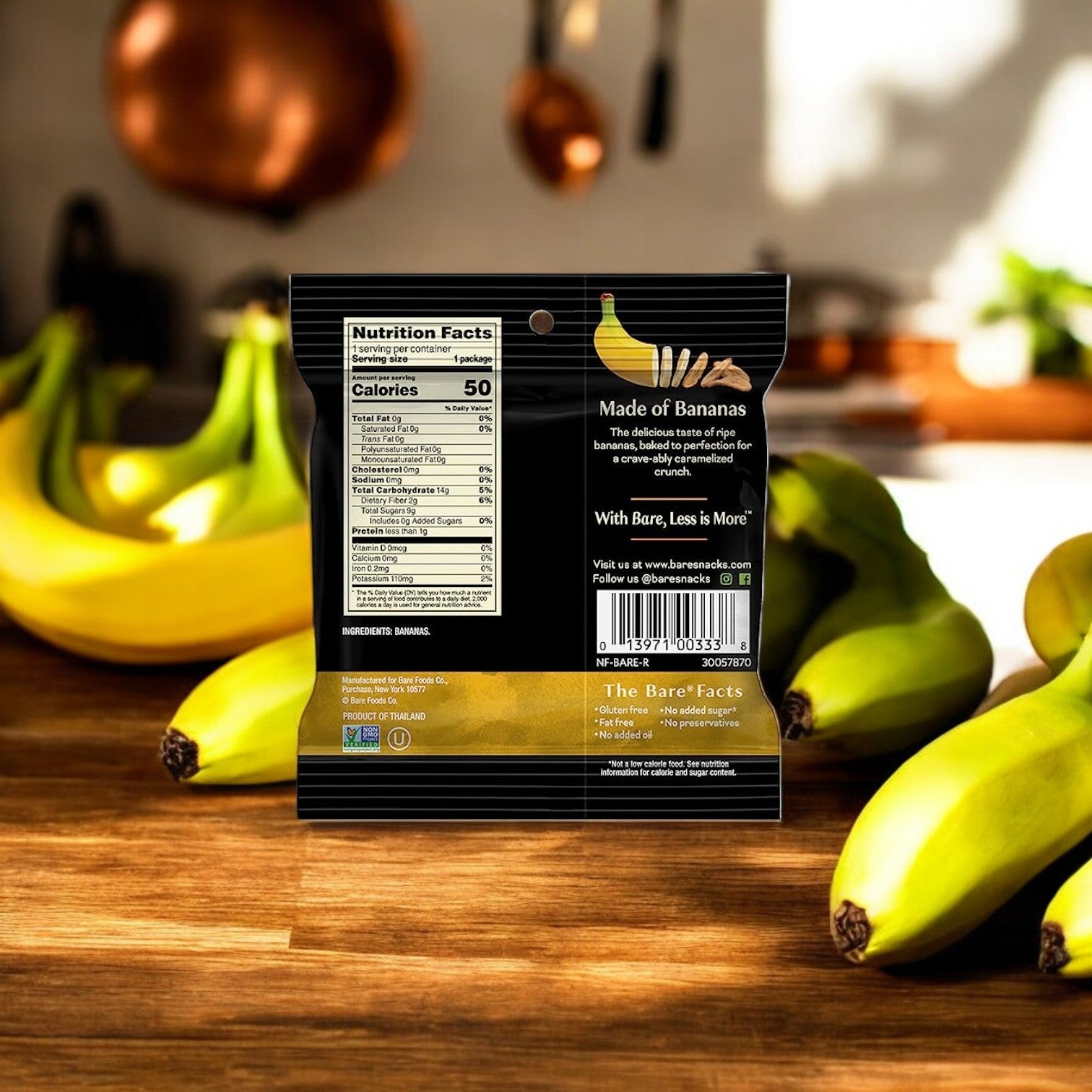 A package of Easy Lunches Bare Baked Crunchy Simply Banana Flavor, 0.53 oz., 1 Count is shown with the backside facing forward, displaying nutrition facts. Several whole bananas are in the background on a wooden surface.