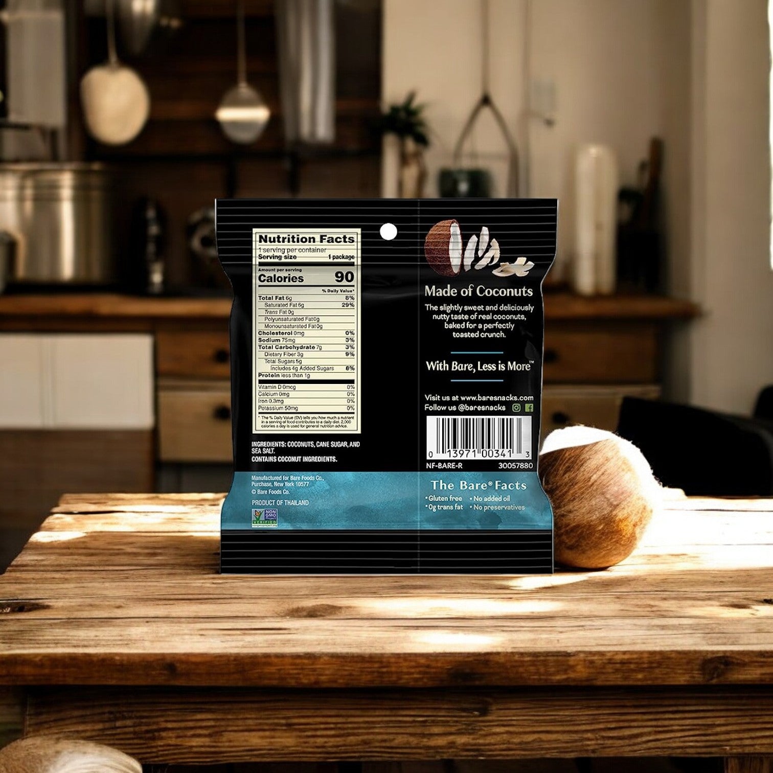 A packet of coconut-based snacks is placed on a wooden table in a kitchen. The packet, labeled "Bare Baked Crunchy Toasted Coconut Flavor," displays nutritional facts and the brand's tagline, "With Easy Lunches, Less is More." Enjoy this healthy 0.53 oz snack as a perfect single-serve option for any time of day.