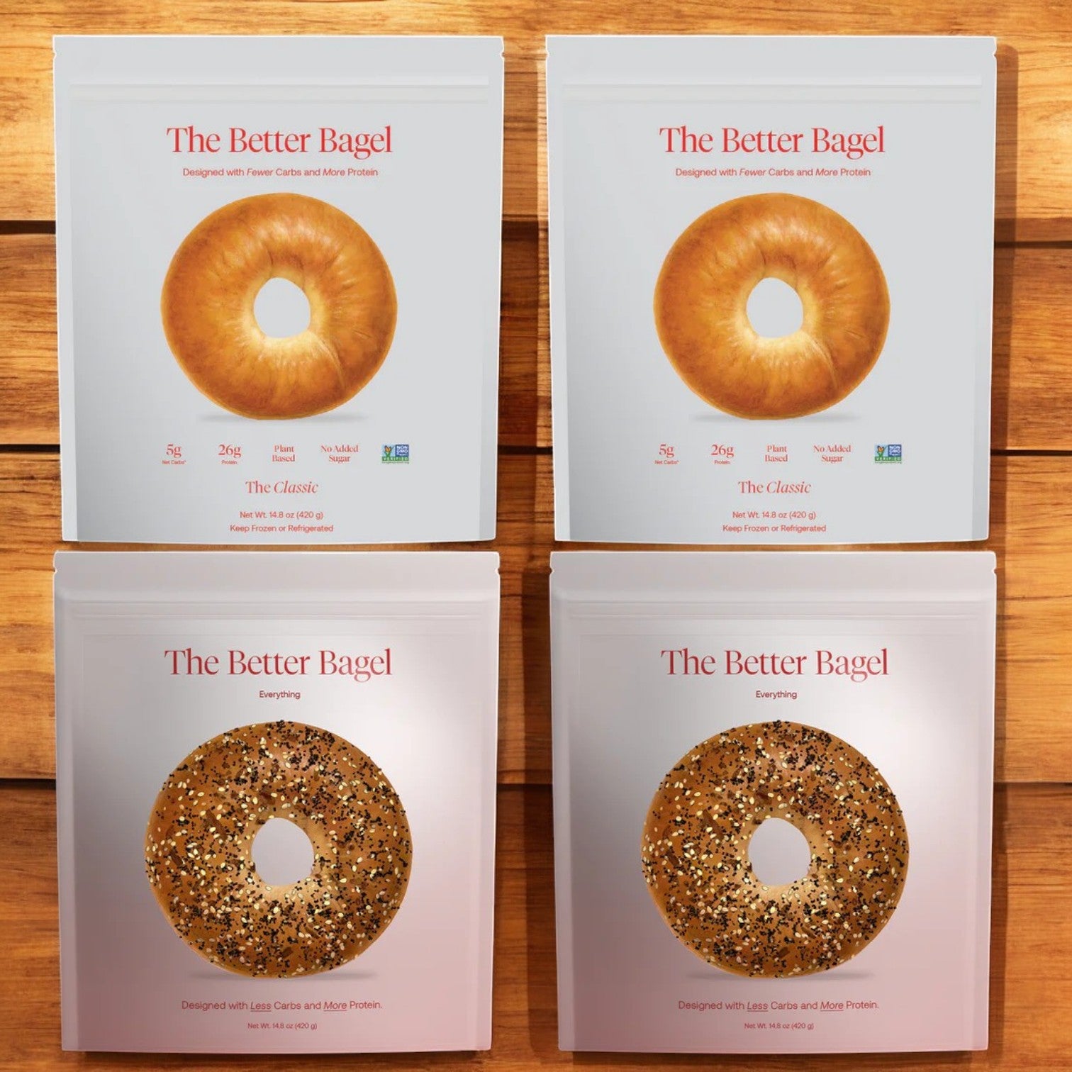 Four packages of Better Brand Bagels on a wooden background, showcasing the Better Brand Variety Pack, which includes two The Classic Bags and two The Everything Bags, for a total of 16 bagels.