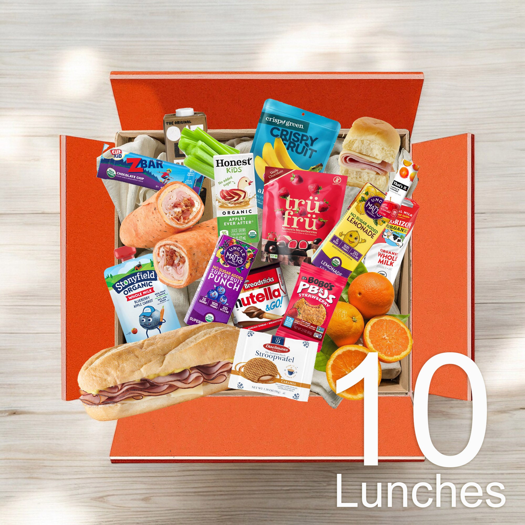 An open box labeled "Kids 10 Lunch Bundle" from Easy Lunches, available at $8.99 per lunch, contains various food items including snacks, fruits, a sandwich, and beverages.