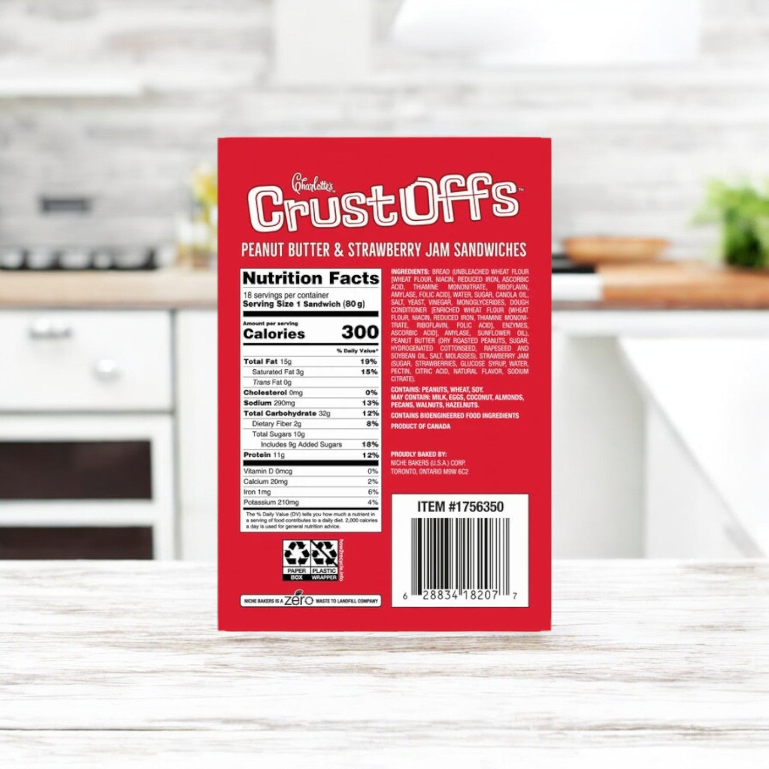 A red box of Easy Lunches' Charlotte's Crust Offs Sandwiches, Peanut Butter & Strawberry Jam, 2.2 oz., is on the kitchen counter, highlighting its tasty blend of peanut butter and strawberry jam with nutrition facts and ingredients listed on the back.