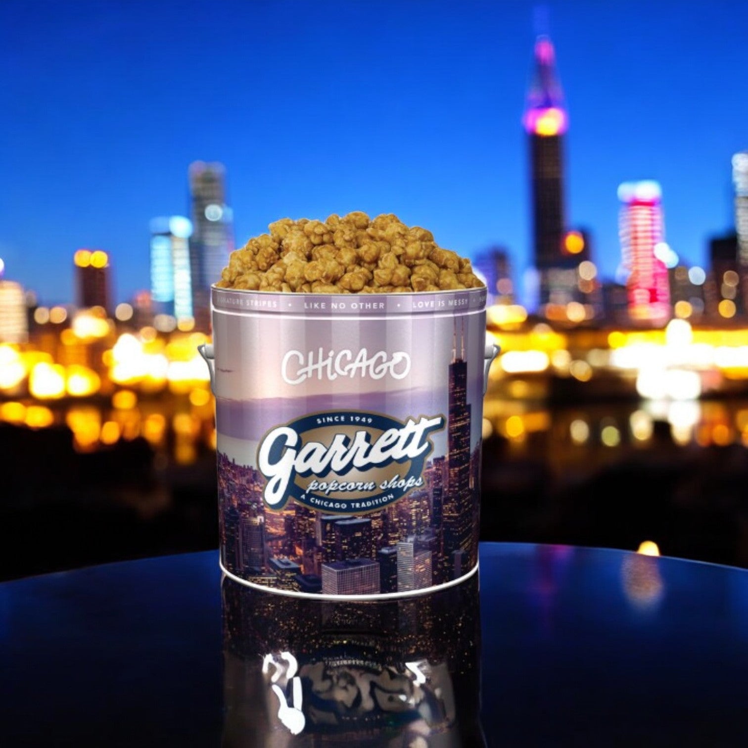 A "Best of Chicago Sampler! 5 Items Total!" tin from Easy Lunches is filled with caramel popcorn, set against a blurred city skyline at night.