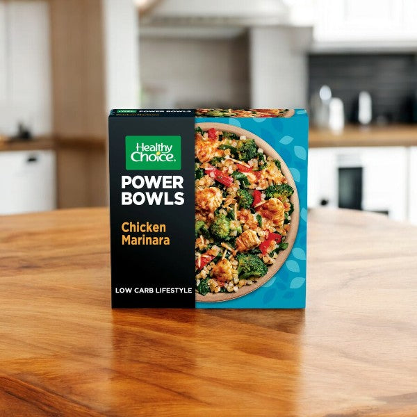 The Healthy Choice Power Bowl Variety Pack, featuring an assortment of 2 Korean Style Chicken, 2 Adobo Chicken, 2 Chicken Marinara, and 2 Greek Style Chicken - totaling 8 delicious Power Bowls, sits on a wooden countertop in a cozy kitchen. Enjoy the convenience of these nutritious and microwaveable meals from Healthy Choice that make healthy eating easy and satisfying.