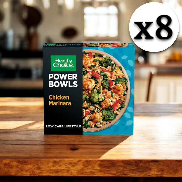 An 8-count box of Healthy Choice Power Bowls Chicken Marinara With Riced Cauliflower, 9.25 oz., sits on a wooden table in a kitchen.