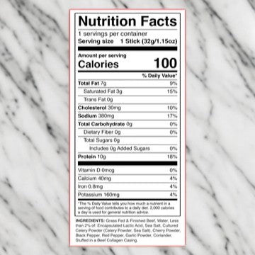 A nutrition label on a marble surface detailing information per 32g serving size, including 100 calories, 7g total fat, 0g trans fat, 30mg cholesterol, 380mg sodium, 0g total sugars, and 10g protein. This Chomps Zero Sugar Original Beef Jerky Stick is made from grass-fed Non-GMO beef and is Paleo Whole30 Keto-friendly.