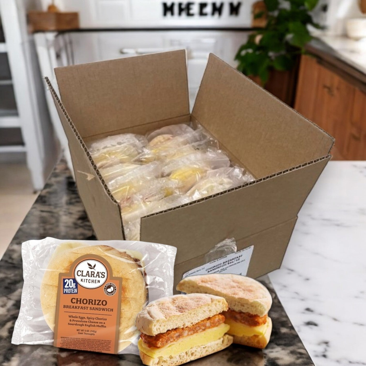 An open case of Clara's Kitchen Individually Packaged Chorizo Breakfast Sandwiches, 5oz - 3 Packs, sits on the counter with one package and two half sandwiches visible. Enjoy a convenient breakfast with these individually packaged delights.