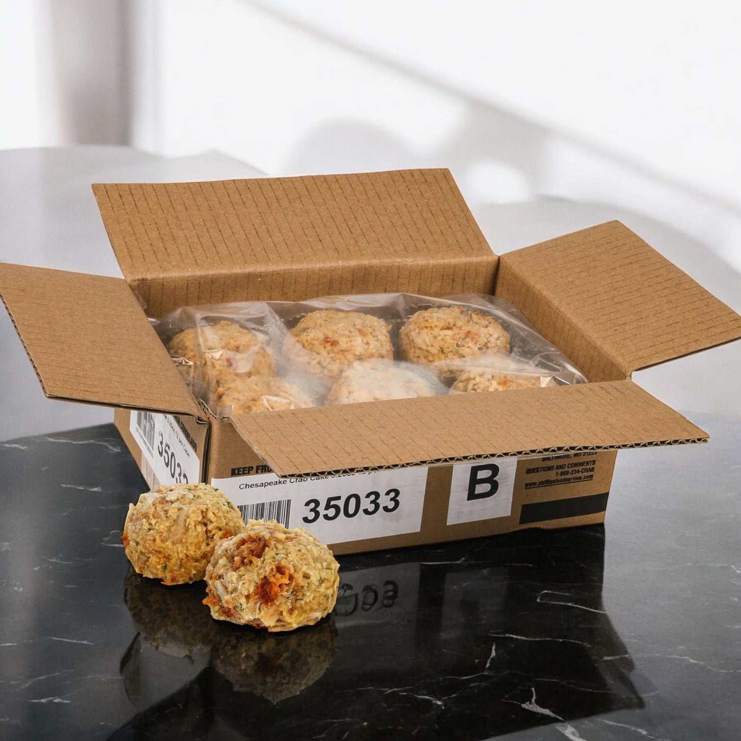 A box of Phillips Foods products includes several packaged scone-like baked goods, reminiscent of authentic Chesapeake flavor, with two unpackaged on a black marble surface.