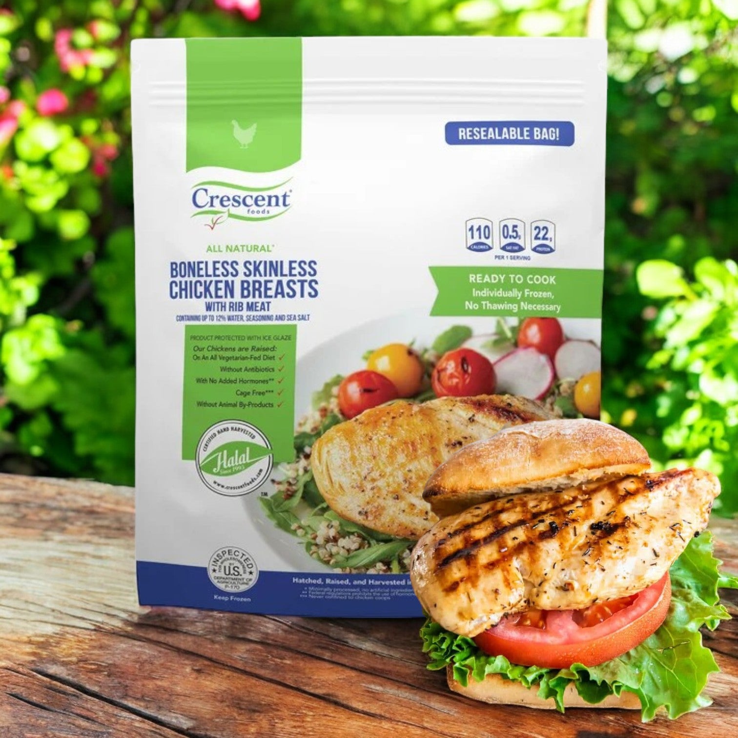 A pack of Crescent Foods Halal Chicken Breast, 5 lbs, displayed outdoors features a grilled chicken sandwich in the foreground, providing a delicious source of high-quality protein.