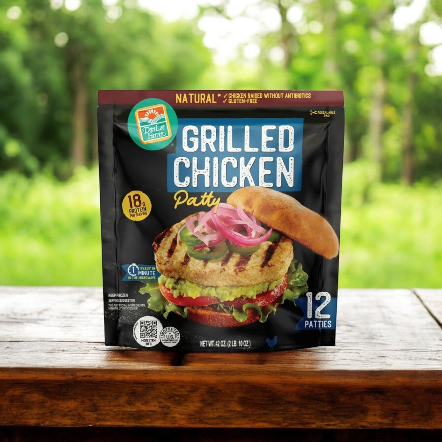 A bag of Don Lee Farms Chicken Patties on an outdoor wooden table features 12 fully cooked, all-natural patties with lettuce and pickled onions.