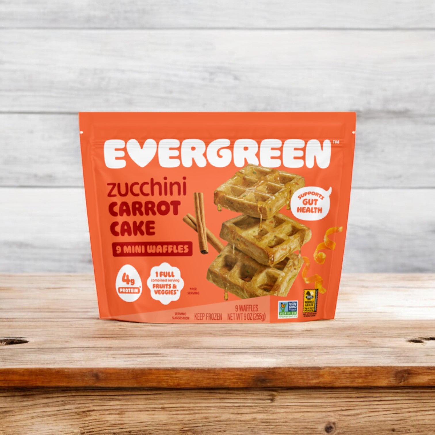 Displayed on a wooden surface, the Evergreen Frozen Zucchini Carrot Cake Mini Waffles, 9 oz., offer a nutritious breakfast option. They emphasize health benefits such as "supports gut health" and contain "4g protein," making these mini waffles an excellent choice to kickstart your day.