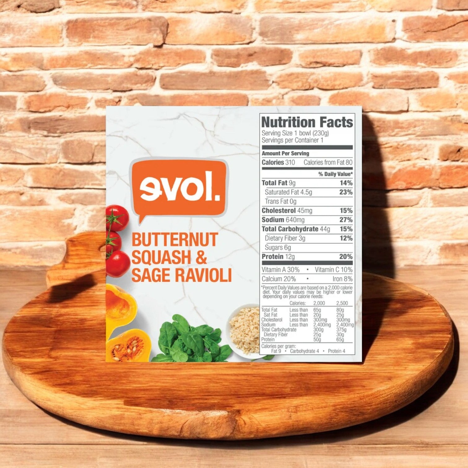 An 8.13 oz box of Evol Vegetarian Butternut Squash & Sage Ravioli, prominently displaying its nutrition facts label, sits on a wooden cutting board. This single-serve meal pairs perfectly with our Vegetarian Truffle Parmesan Mac and Cheese for a delightful combination.