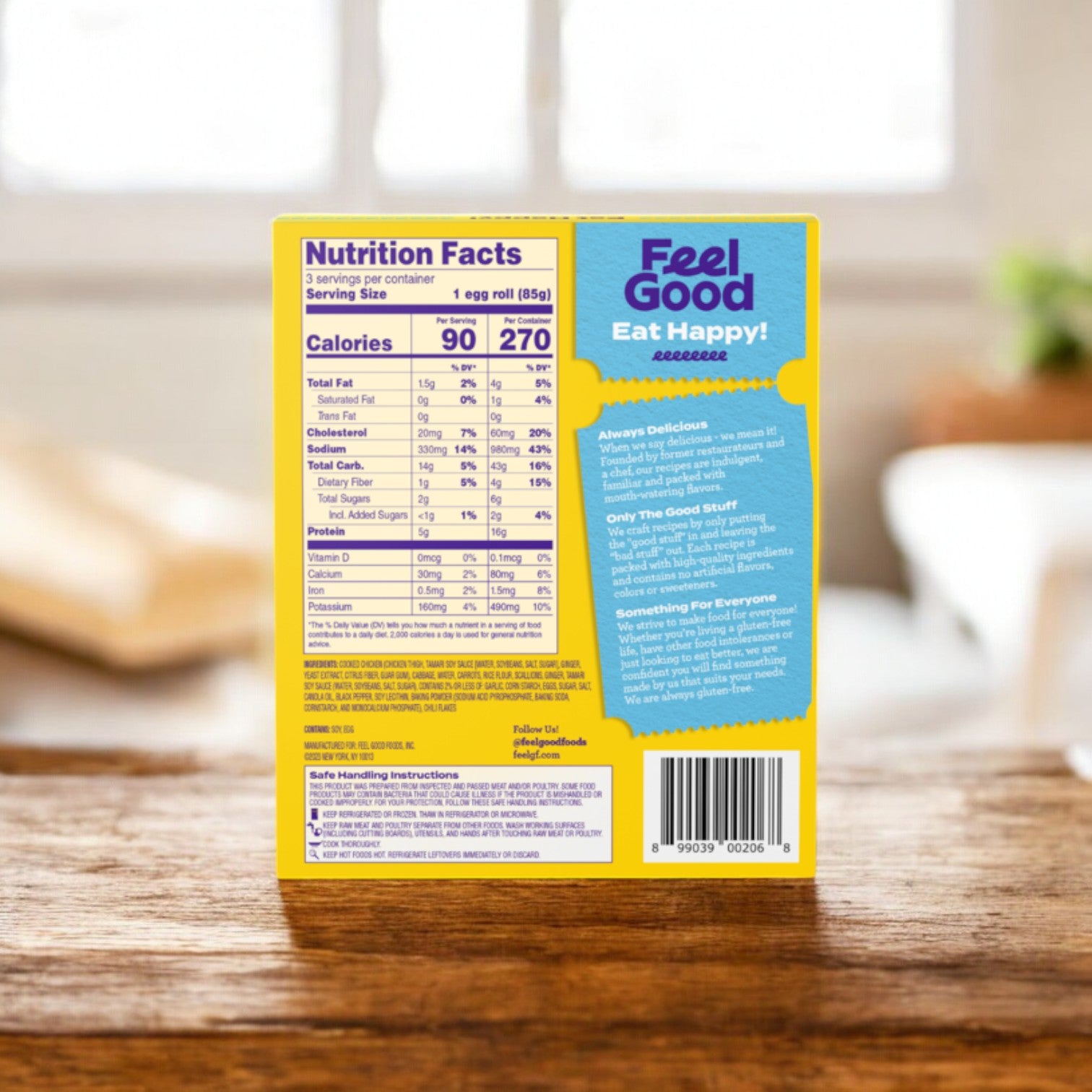 Close-up of a box of Feel Good Foods Gluten-Free Chicken Egg Rolls showcasing nutritional facts and marketing text. The phrase "Feel Good Eat Happy!" is displayed in blue against a yellow backdrop, much like choosing a quick snack with a crispy shell for your day. In the background, there's a blurred kitchen setting that promises comfort and ease.