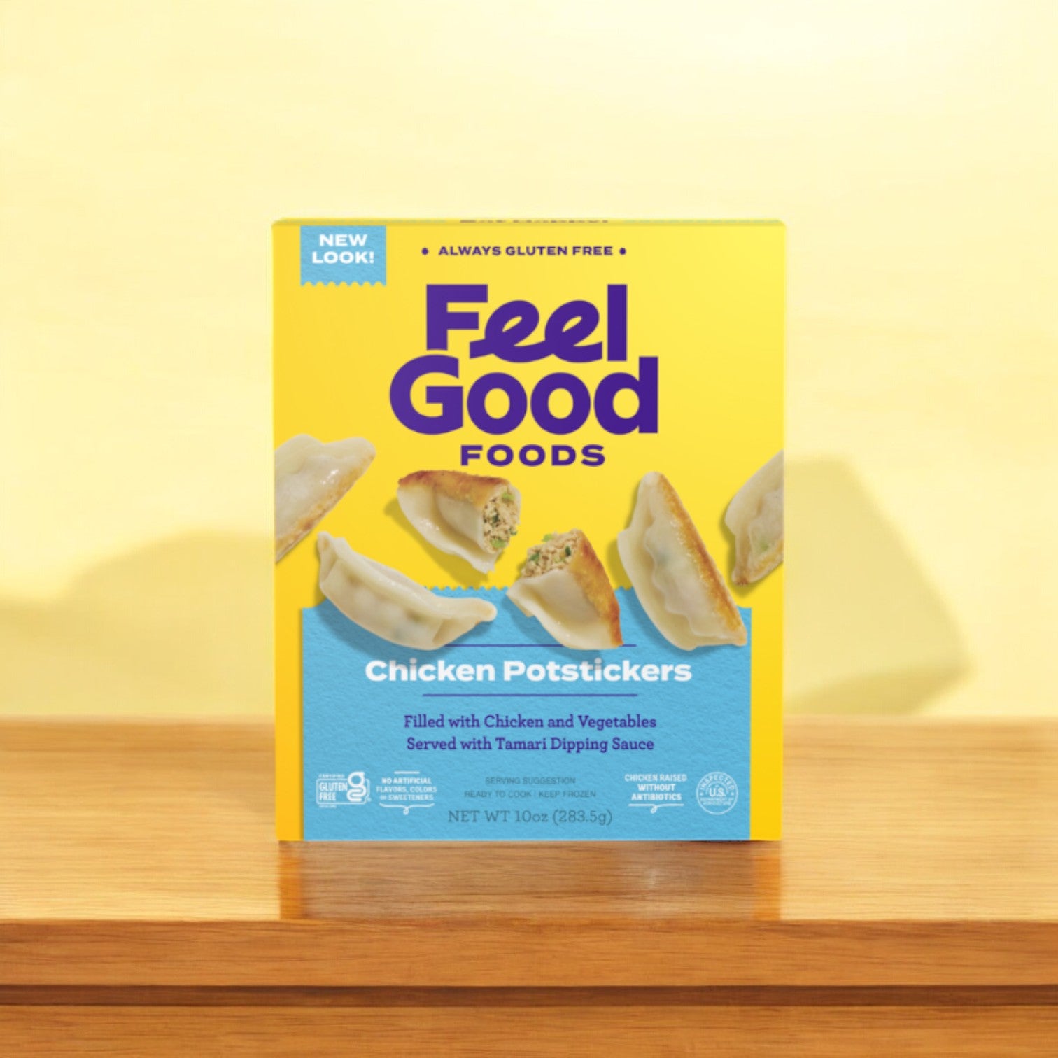 A box of Feel Good Foods' Gluten-Free Chicken Potstickers, 10 oz. - 1 Count, is placed on a wooden surface against a yellow backdrop. The packaging emphasizes its mouth-watering Asian flavors and the inclusion of tamari dipping sauce, all encased in gluten-free dough.