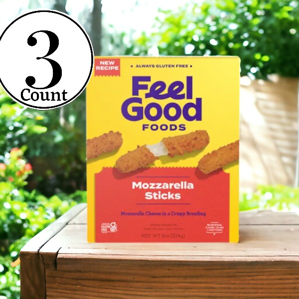 Three boxes of Feel Good Foods Gluten Free, Breaded Mozzarella Sticks are displayed on a wooden table outside. Each box is proudly labeled "New Recipe," "Always Gluten Free," and contains an 8 oz portion. These comfort foods make the perfect shareable snacks for any gathering, offering delicious flavors everyone can enjoy.