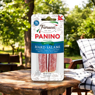 The Fiorucci Hard Salami and Mozzarella Cheese Panino, a savory snack featuring hard salami wrapped around mozzarella cheese, is photographed on a wooden table outdoors in its convenient 1.5 oz grab-and-go size.