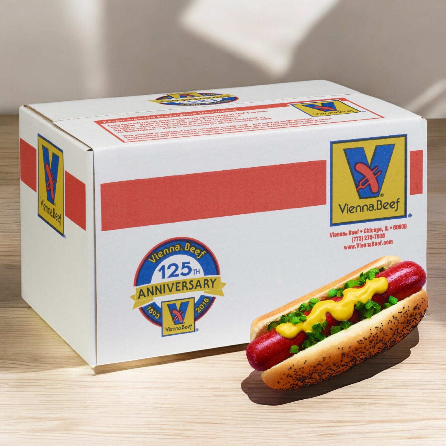 The Vienna Beef 125th Anniversary box sits elegantly beside a premium all-beef Vienna Franks hot dog, topped with mustard and relish on a wooden surface.