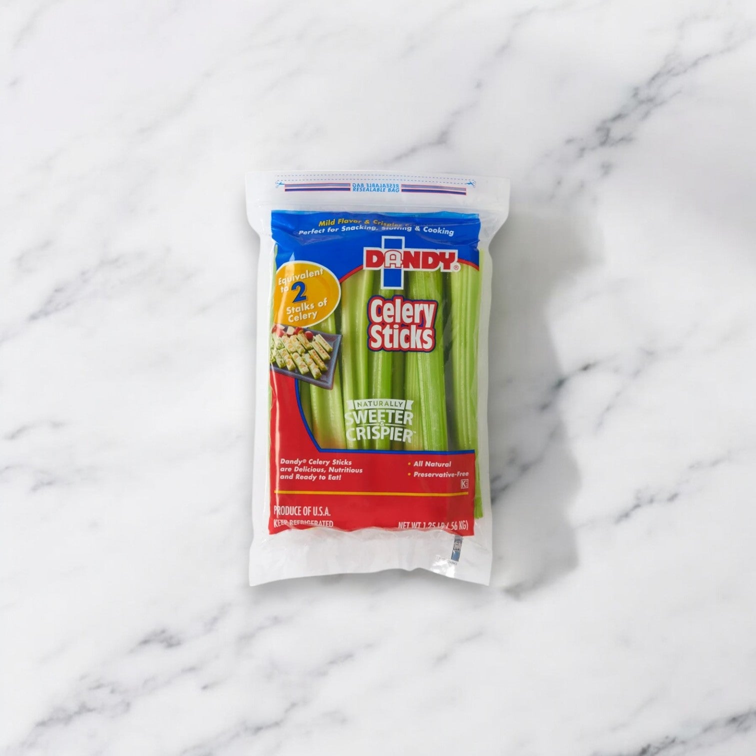 A sealed bag of Easy Lunches brand Fresh Celery Sticks, 20 oz - 1 Bag, placed on a marble surface. The packaging is primarily blue and red with a window displaying the nutritious, low-calorie snack inside.