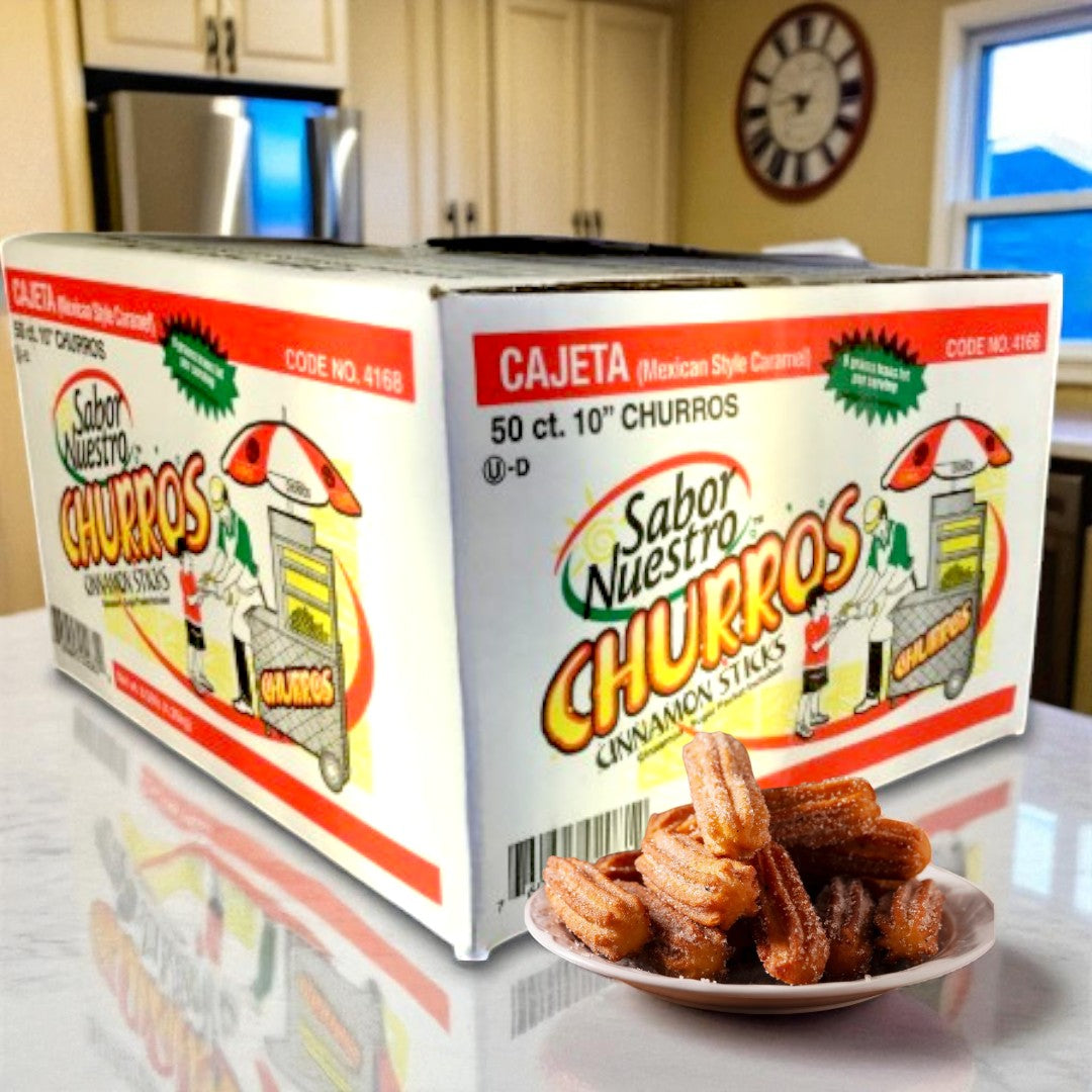 A large box of Sabor Nuestro Frozen Cajeta-Filled Churros – 10" (50 ct) sits on the kitchen counter, with a plate of these delicious Mexican churros displayed in front.