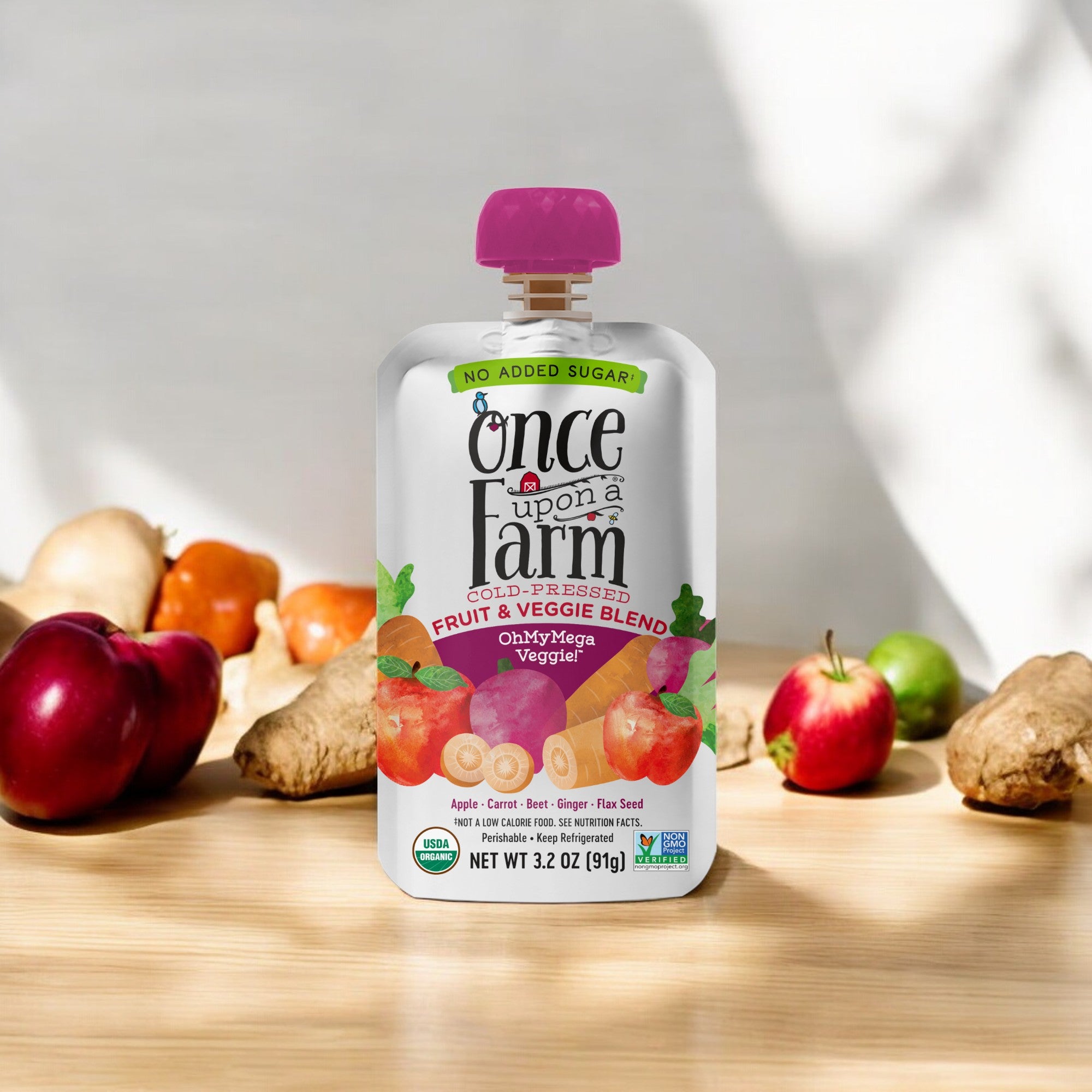 A pouch labeled "Once Upon a Farm OhMyMega Veggie," containing an Organic Fruit & Veggie Blend with no added sugar, sits on a wooden surface with assorted fruits and vegetables in the background.