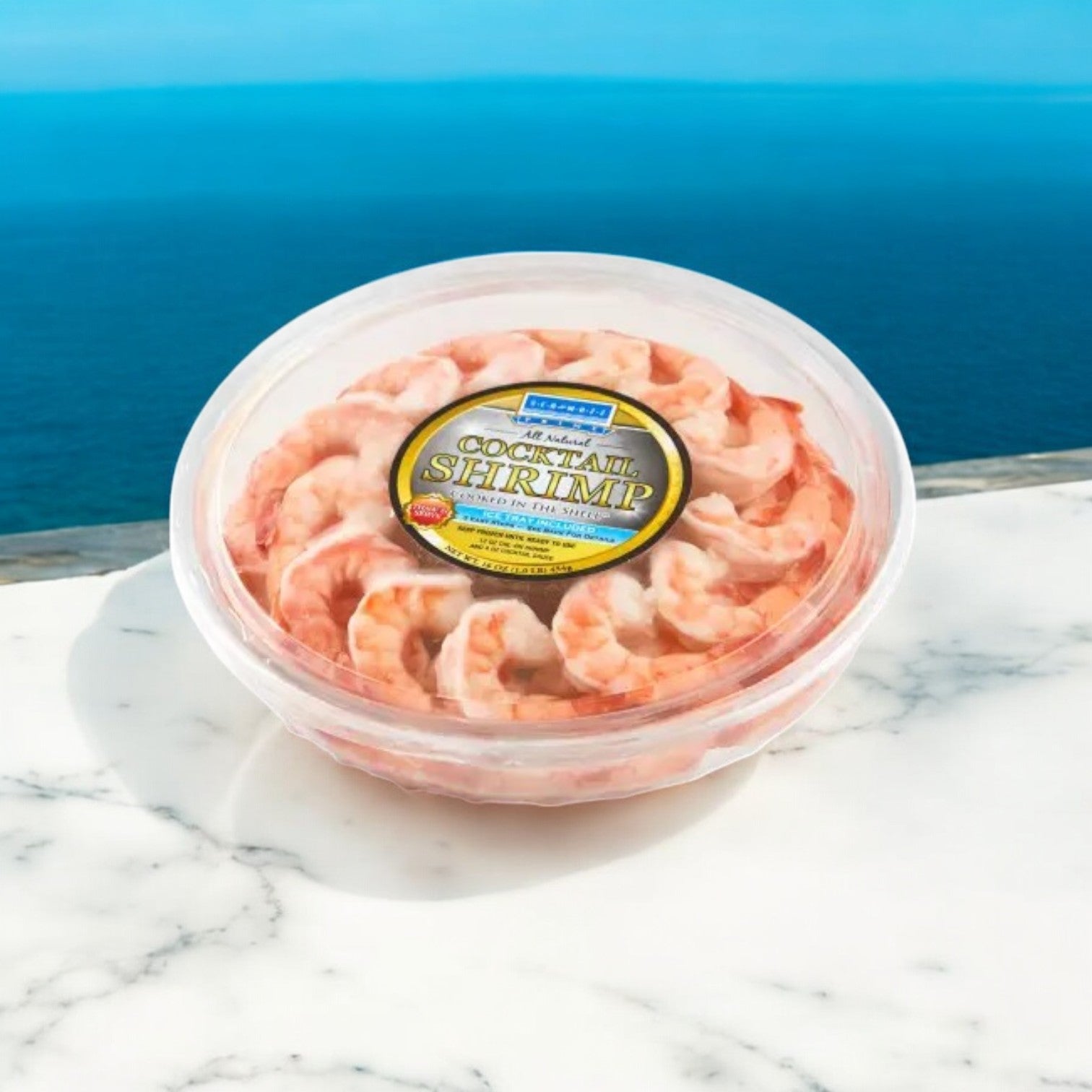 A plastic tray of Easy Lunches Shrimp Platter - Seamazz Fully Cooked Cocktail Shrimp Ring (16 oz., 3 packs) is displayed on a white marble surface with the ocean in the background, ready to serve as a tasty appetizer.