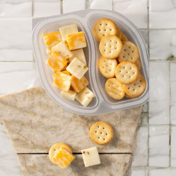 Sargento Balanced Breaks Cheese and Crackers: A plastic tray containing Sargento's natural cheese square pieces on one side and round crackers on the other, elegantly placed on a marble surface.