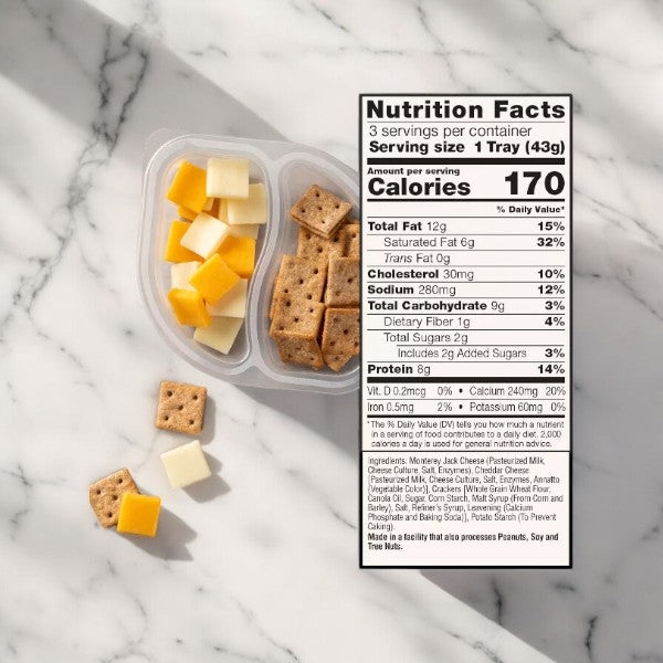 A Sargento Balanced Breaks Cheese & Mini Wheat Thin Crackers container from Easy Lunches sits next to a nutrition facts label on a marble surface.