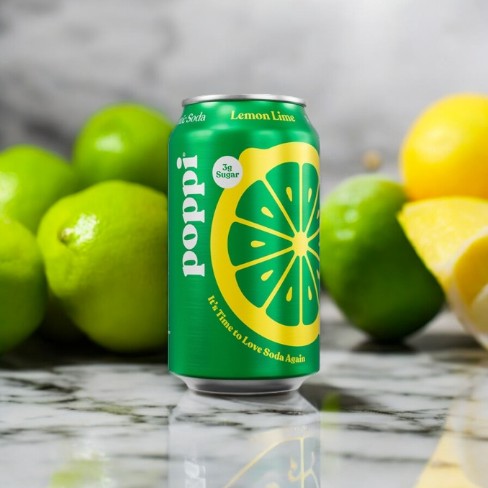 A Poppi Prebiotic Soda, Lemon Lime, 1-12 fl oz Can is placed on a marble surface with whole and cut lemons and limes in the background, showcasing the refreshing drink from Poppi that wowed investors on Shark Tank.