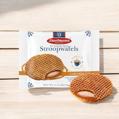 Place the Daelmans Individually Wrapped Caramel Stroopwafel - 2.75 oz - 1 Count on a light surface. The packaging features a white background with blue and red accents, displaying the Daelmans brand name and product name alongside an image of a cup of coffee. These Dutch delights are made with natural ingredients, offering delicious caramel stroopwafels.