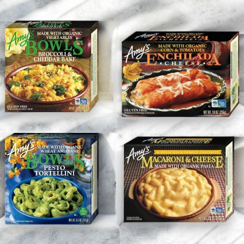 Four boxed meals from Amy's are displayed: Broccoli & Cheddar Bake, Enchilada Cheese, Pesto Tortellini, and Macaroni & Cheese. Each package features the product image and labeling under the branding "Amy's Bowls Meal Bundle! 1 Broccoli Cheddar Bake, 1 Enchilada Cheese, 1 Pesto Tortellini, 1 Macaroni & Cheese - 4 Total Meals!