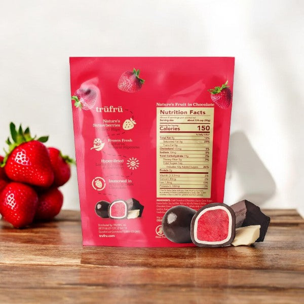 A package of Tru Fru Chocolate Covered Strawberry's (4.2 oz - 1 Count) is displayed on a wooden surface alongside fresh strawberries, making it perfect for convenient snacking.