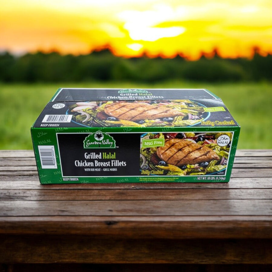 A 10 lbs box of Restaurant Depot Grilled Halal Chicken Breast Fillets, Fully Cooked, rests on a wooden surface outdoors with a sunset and grassy field in the background.