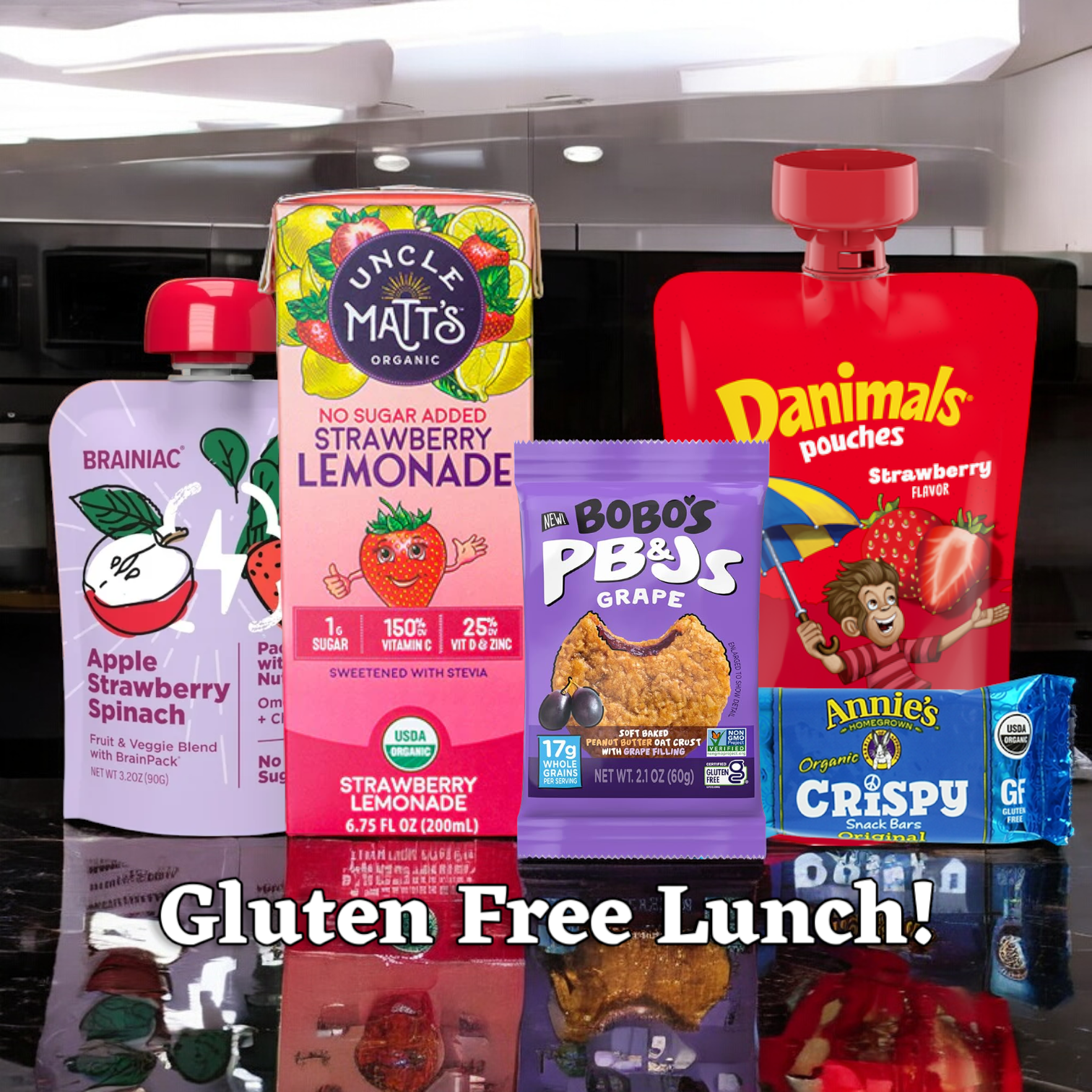 Easy Lunches' Gluten Free Lunch! features a selection of five gluten-free items including an Apple & Strawberry Brainiac Pouch, an Uncle Matt's Strawberry Lemonade Juice Box, a Bob's Grape PB&J Bar, and an Annie's Crispy Bar displayed on a countertop.