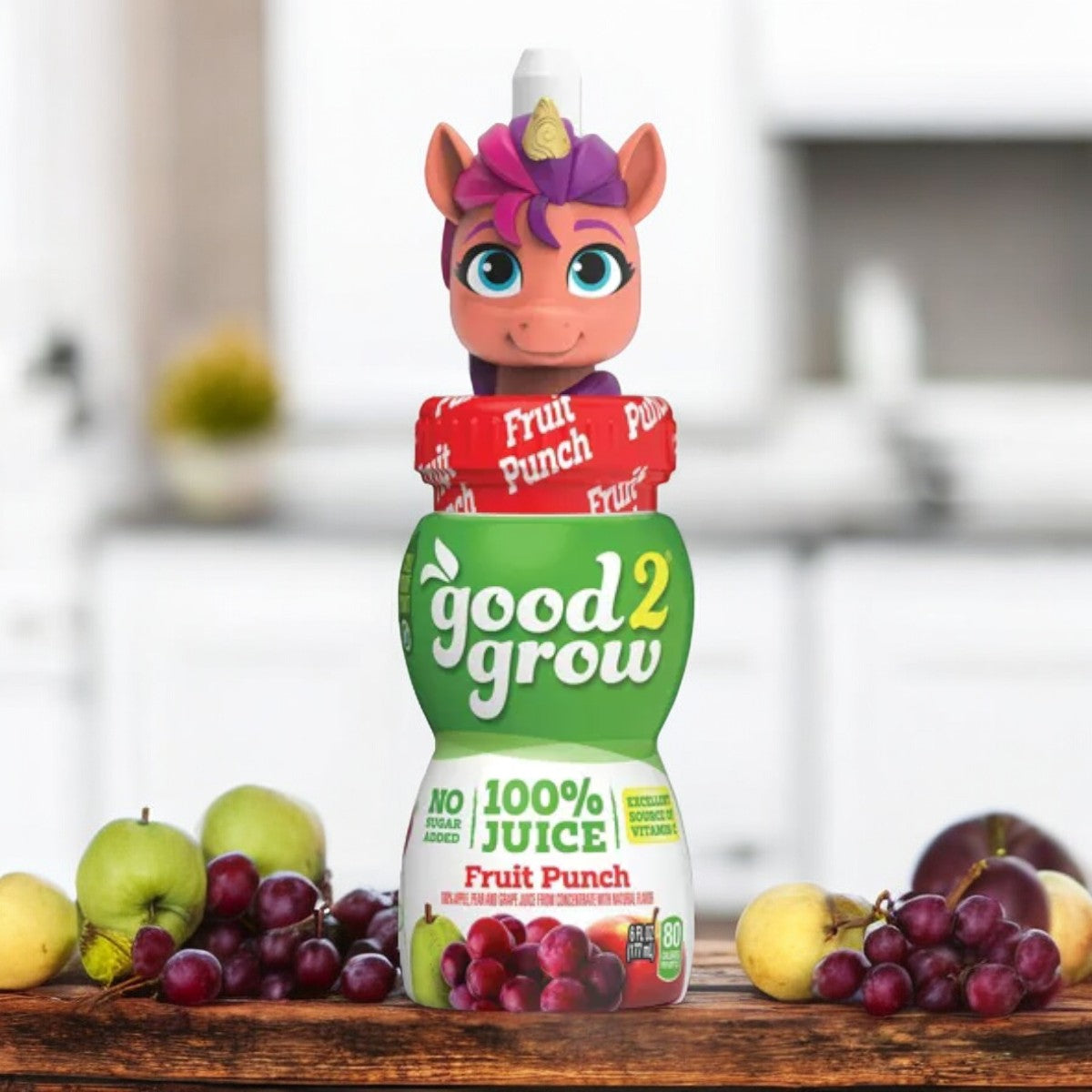 A bottle of Easy Lunches' Good2Grow Fruit Punch Juice Single Serve, 6 oz - 1 Count (with a collectible horse character top) sits on a wooden table in a kitchen setting, surrounded by apples, lemons, and grapes. Enjoy 100% juice that's both fun and nutritious!