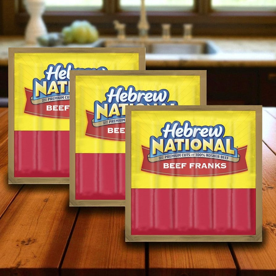 Three packs of Easy Lunches Hebrew National Beef Franks, 10.3 oz each, are displayed on a wooden kitchen surface with a blurred background.