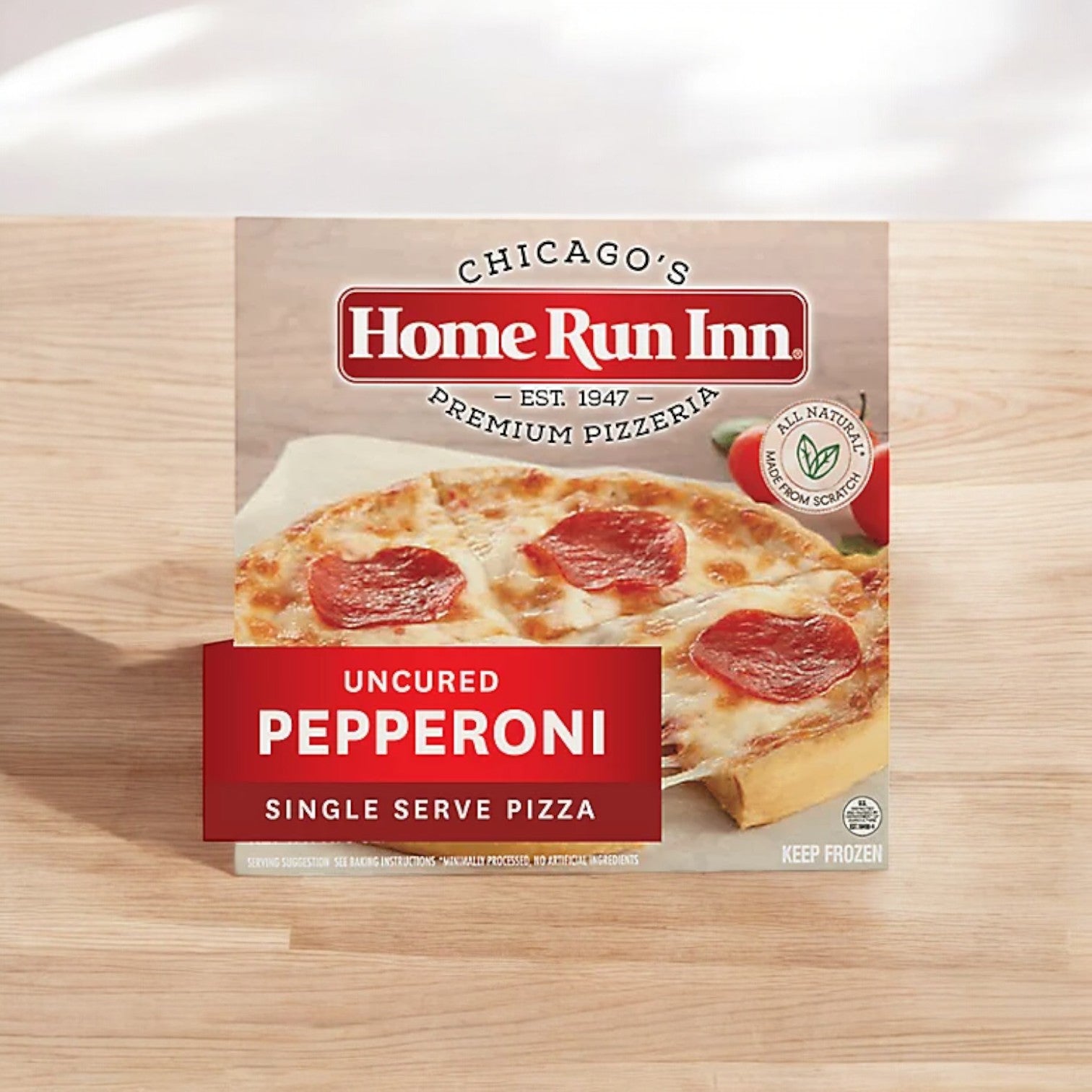 A box of Home Run Inn Classic Crust Uncured Pepperoni Frozen Pizza (7.75 oz.) is displayed, highlighting the appetizing pizza and its packaging details on a rustic wooden surface.