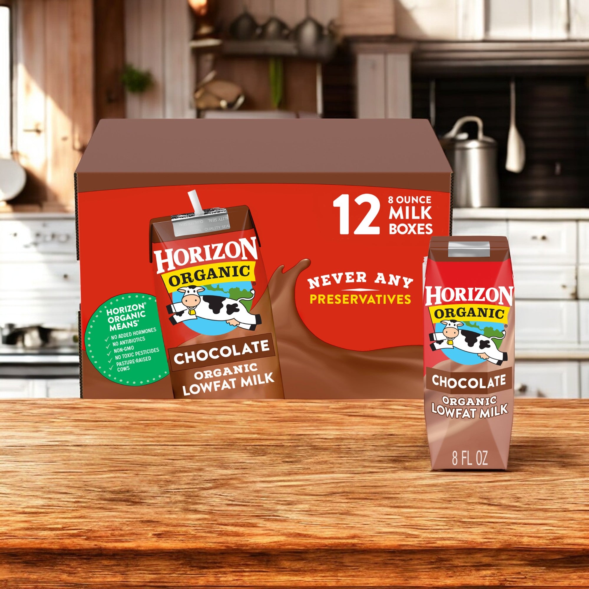 A box containing 24 individual cartons of Organic Horizon Whole Milk & Chocolate Milk from the Easy Lunches brand is displayed on a wooden counter in a kitchen setting. One carton is positioned outside the box.