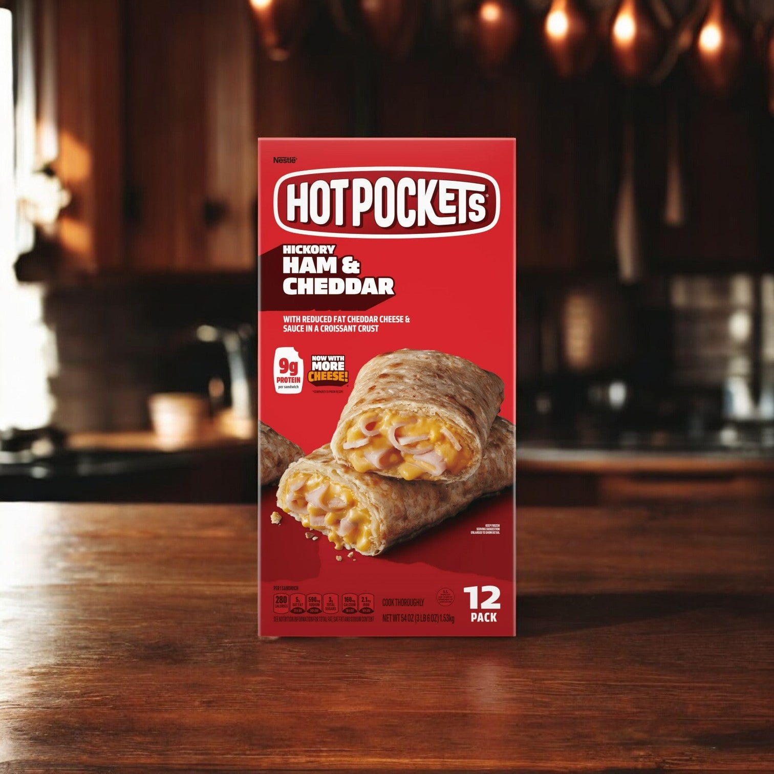 A box from the Hot Pockets Variety Pack, featuring Meatballs and Mozzarella Cheese, Pepperoni Pizza, and Ham and Cheddar Croissant Crust flavors, sits on a wooden kitchen counter. The packaging, part of their popular frozen snacks line, highlights the assortment of stuffed sandwiches. This convenient pack includes 36 total Hot Pockets spread across three flavors in three boxes.