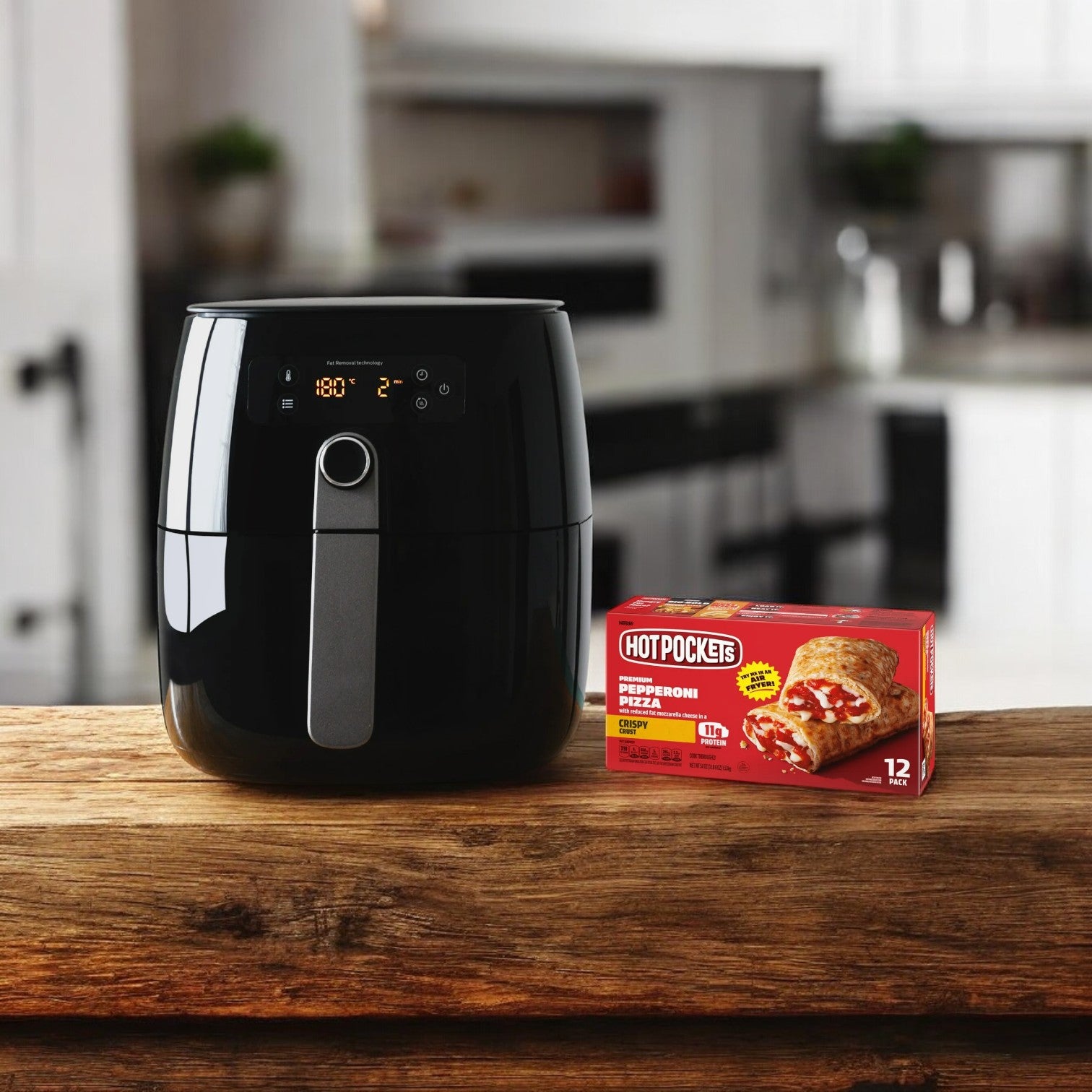 A black air fryer sits on a wooden countertop next to a pack of Hot Pockets Frozen Snacks, Pepperoni Pizza Crispy Crust, promising crispy crust sandwiches in a modern kitchen.